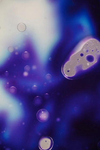 Abstract macro image with fluid-like forms, bubbles, and vibrant color gradients of blue, purple, and white, creating a dreamy, ethereal effect.