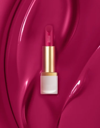 Magenta lipstick tube resting vertically on a glossy deep pink liquid textured backdrop styled by Alex Brannian