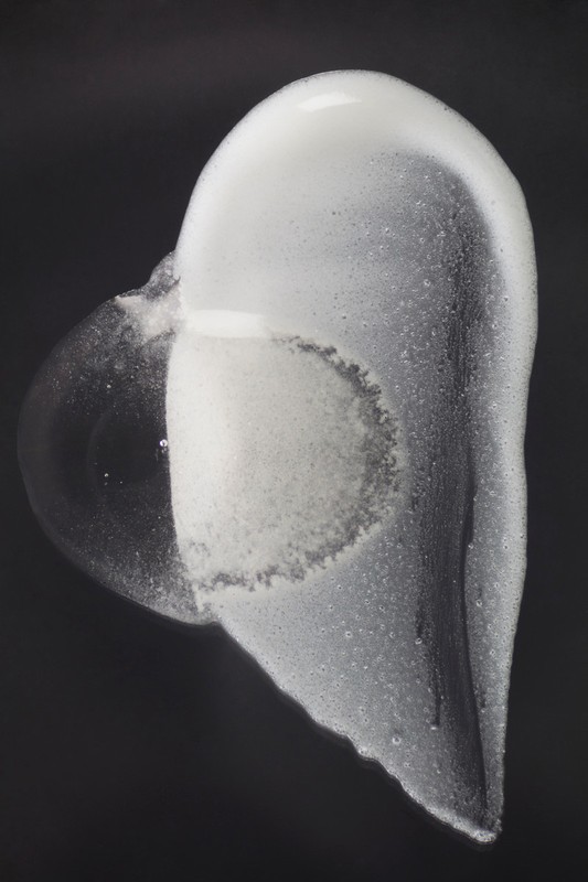 Abstract still life of white soap foam cascading on a dark background. Bubbles and textures create a minimalist, contemporary image.