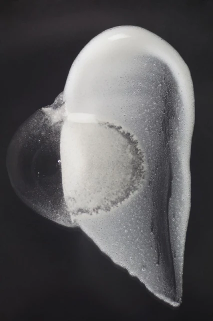 Abstract still life of white soap foam cascading on a dark background. Bubbles and textures create a minimalist, contemporary image.
