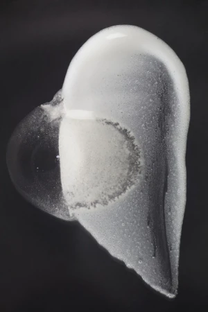 Abstract still life of white soap foam cascading on a dark background. Bubbles and textures create a minimalist, contemporary image.