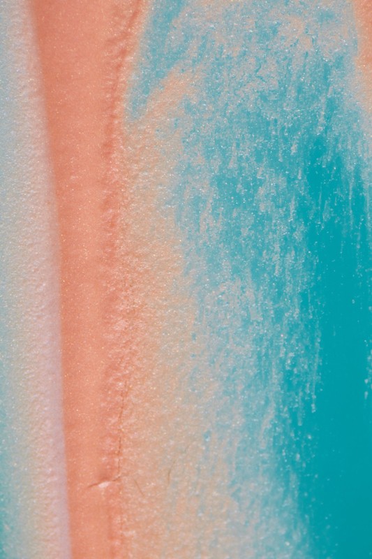 Abstract close-up of light turquoise and coral colors blending, creating a textured, marbled appearance with subtle tonal gradations.