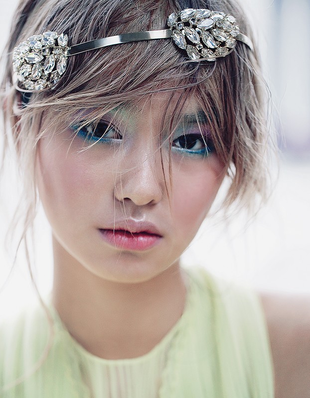 Asian woman with jewel headband and colorful makeup in a close-up shot. Beauty and fashion portrait. Cosmetic and personal care product.