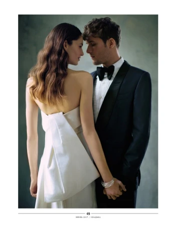 Portrait of a loving couple, the woman in an elegant white dress and the man in a stylish black tuxedo, standing in a close embrace.
