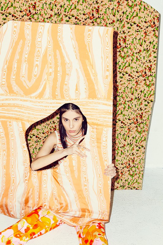 A woman poses with an orange pattern against a similar backdrop in a fashion setting, showcasing contemporary studio portrait photography.