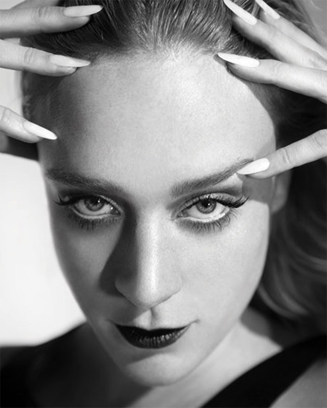 Close-up monochrome portrait of a woman with long white fingernails touching her hair, styled by Alison Lewis.