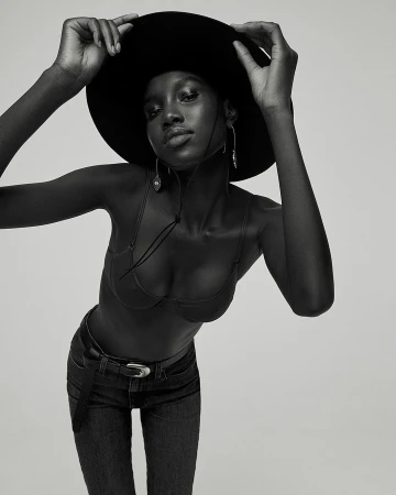 Black and white portrait of a woman wearing a wide-brimmed hat, bra top, and jeans by Amanda Pratt.