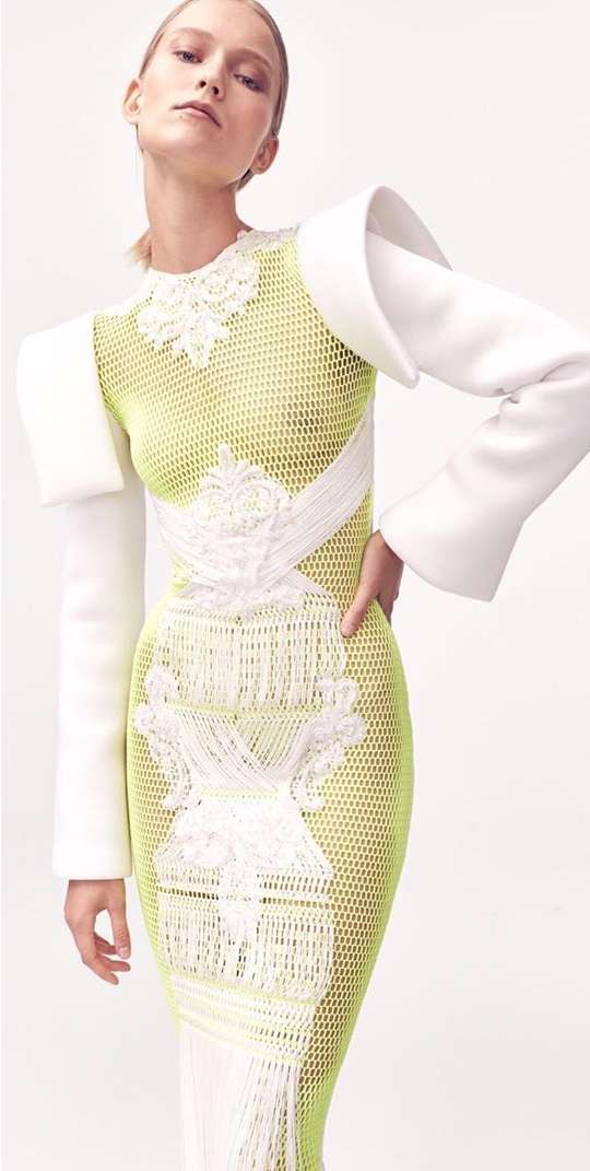 Blonde fashion model wears fitted white and green dress in a bright studio. Fashion, beauty and portrait photography.