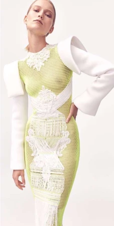 Blonde fashion model wears fitted white and green dress in a bright studio. Fashion, beauty and portrait photography.