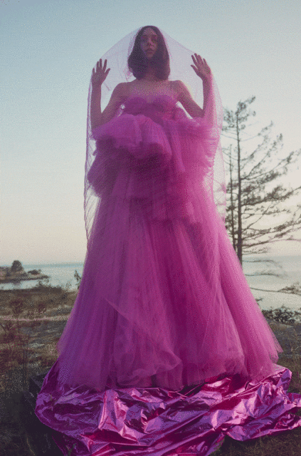 Portrait of a woman with dark hair in a black top against a dark backdrop, utilizing creative lighting to highlight her features.