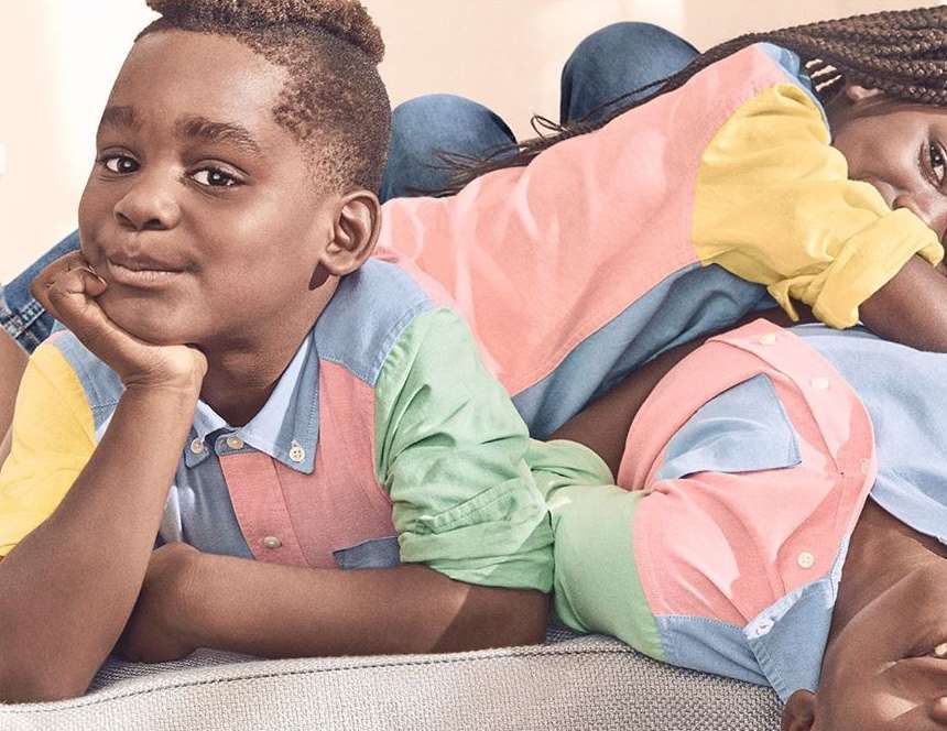 Boy and woman in a colorful shirt lie on a grey couch. A relaxed indoor setting with natural light highlights their casual pose.
