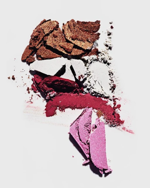 Colorful mix of eyeshadow palettes and powders in shades of pink, white, bronze, and burgundy on a white background, overhead shot.