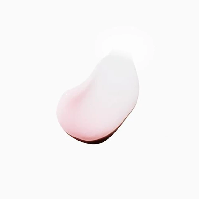 Close-up studio shot of a swirl of pale pink beauty cream on a white backdrop, highlighting its smooth texture and delicate color.