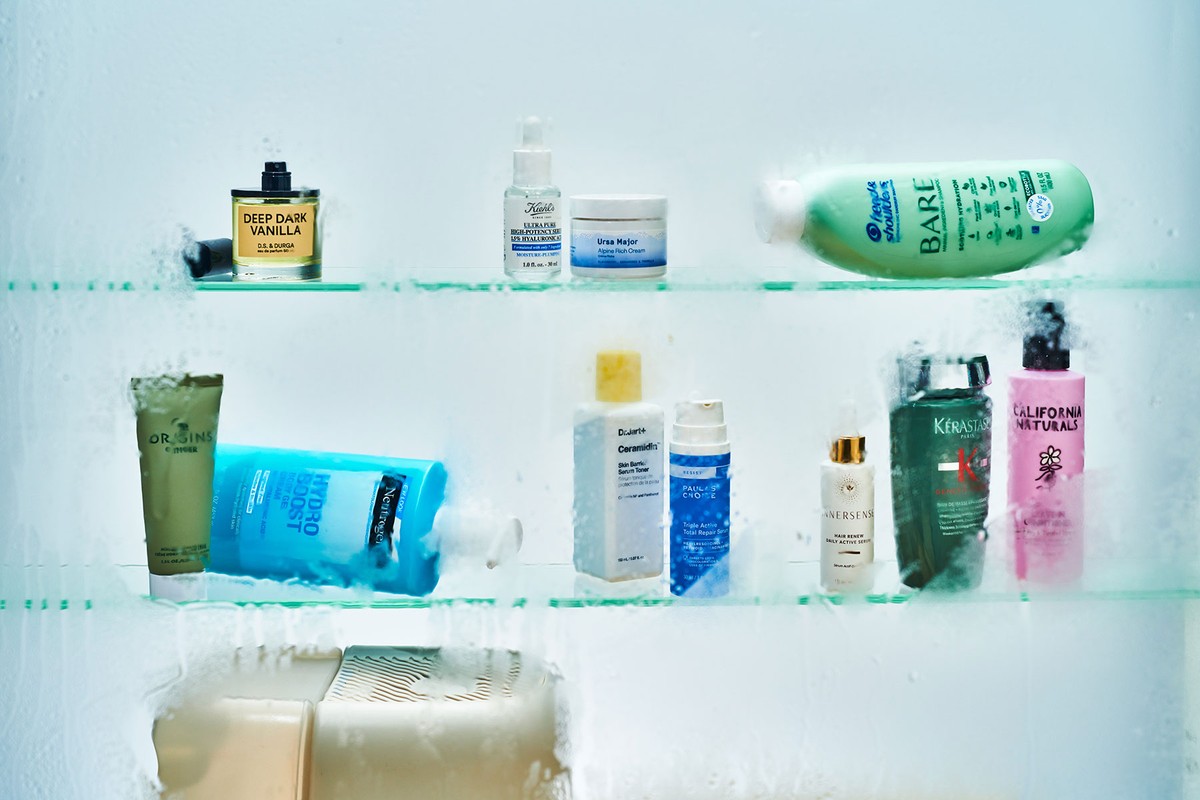 A variety of skincare and haircare products are neatly arranged on glass shelves, showcasing brands like Kiehl's, Neutrogena, and Kerastase.
