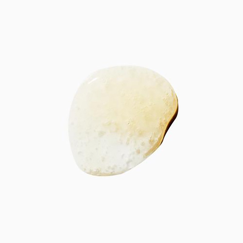Close-up of a yellowish-clear cosmetic serum swatch on a white surface, showing its texture and color.