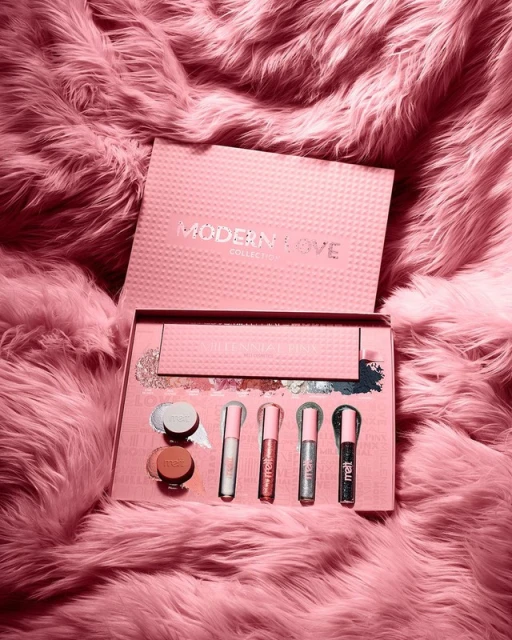 Cosmetic set on a fluffy surface featuring blush, eyeshadow, and lip gloss in pink and silver tones, ideal for beauty product promotions.