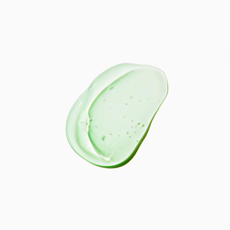 Close-up of a smear of transparent green skincare gel on a white surface, showcasing its texture and color.