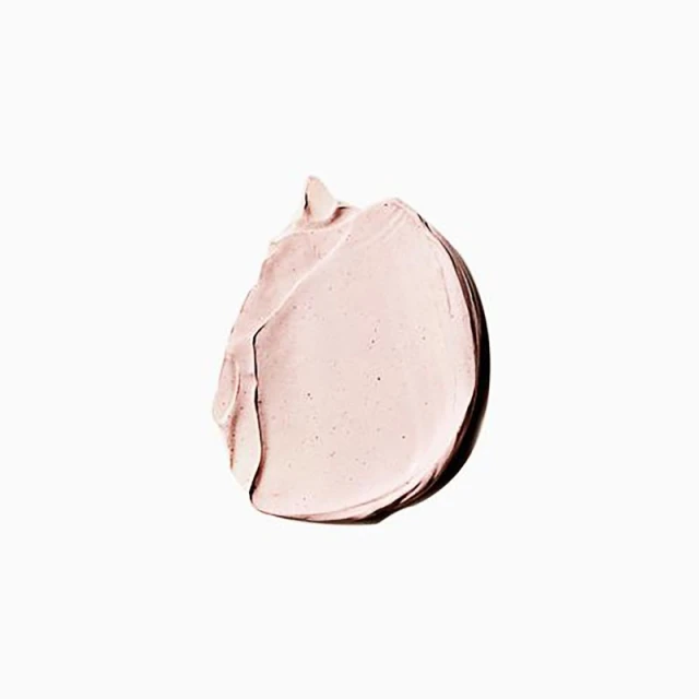Close-up of a smear of pink cosmetic product, highlighting its creamy texture and light rosy hue on a white background.