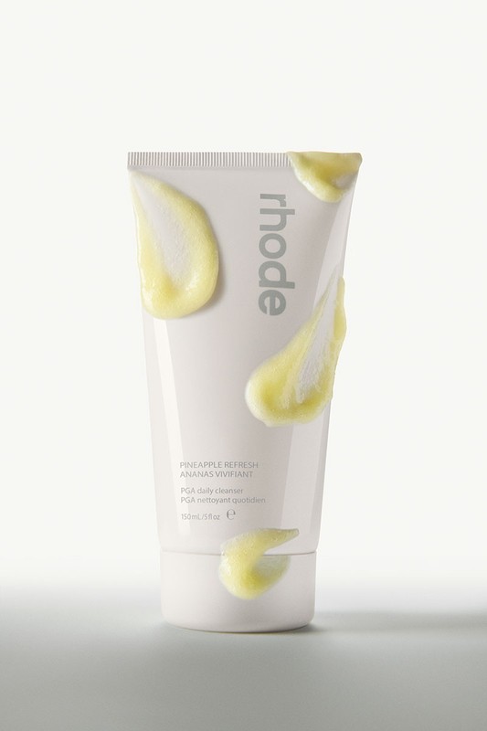 Product shot of a white tube of Rhode Pineapple Refresh cleanser with yellow cleanser smears on the tube against a white background.