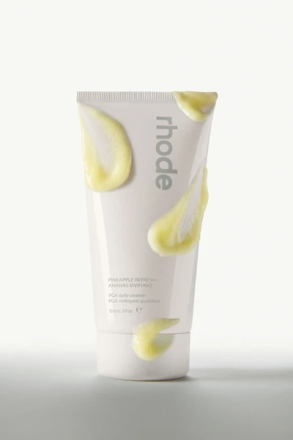 Product shot of a white tube of Rhode Pineapple Refresh cleanser with yellow cleanser smears on the tube against a white background.