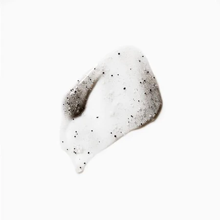 Close-up of a translucent skincare product swatch with visible black exfoliating beads against a clean, bright white background.