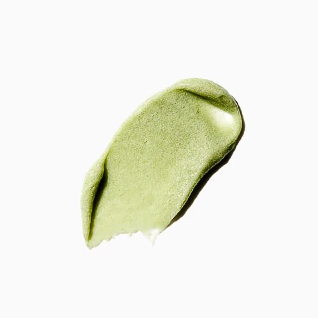 Close-up of a textured smear of light green cosmetic product on a white surface, perfect for beauty and skincare promotions.