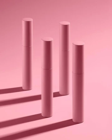 Four pink cosmetic tubes are standing on a pink background with shadows, displayed in a clean, minimalist beauty product promotional image.