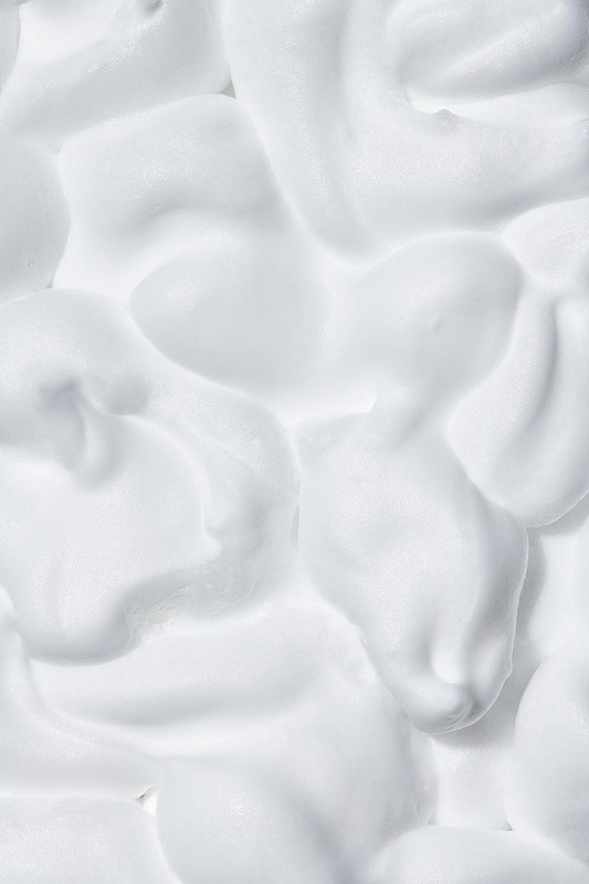Close-up of white foamy texture creating an abstract design, suitable for use in the beauty, healthcare, or food industry. 