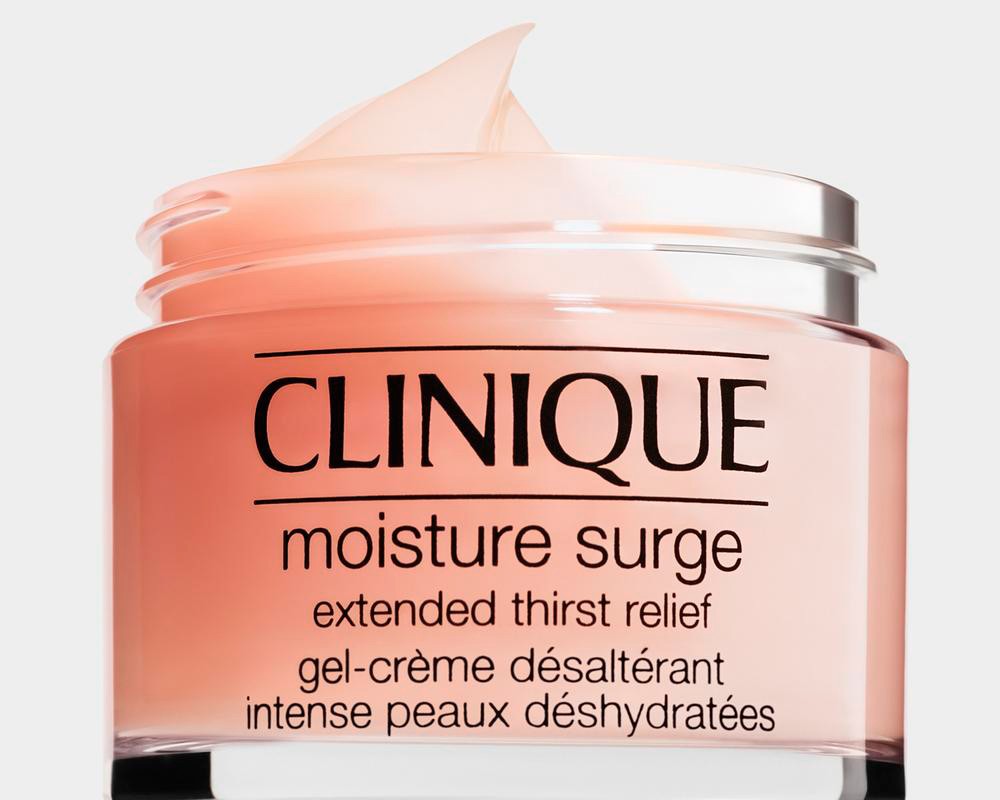 Close-up of a jar of Clinique Moisture Surge skincare product on a plain background. The jar contains pink gel cream.
