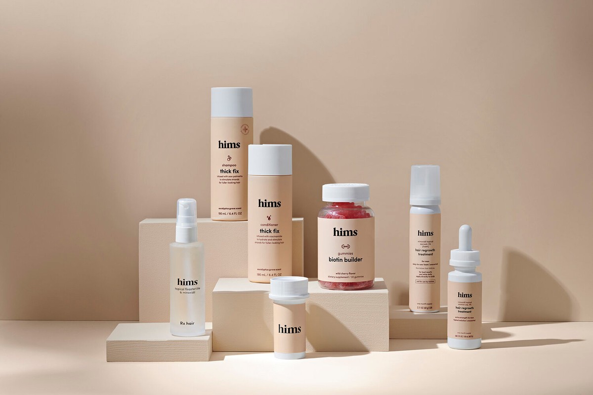 Hims brand hair products on white pedestals, including shampoo, conditioner, hair regrowth treatment, gummies, and topical finasteride.