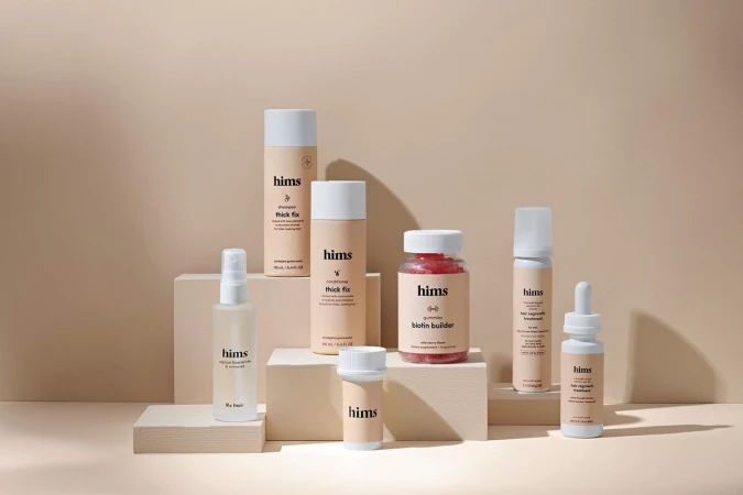 Hims brand hair products on white pedestals, including shampoo, conditioner, hair regrowth treatment, gummies, and topical finasteride.