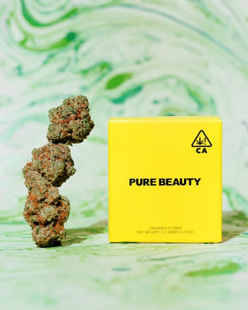 A stack of three cannabis flower buds sits beside a vibrant yellow box labeled 'Pure Beauty' against a dynamic green and white backdrop.