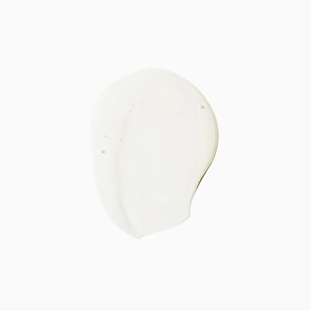 Close-up of an off-white cosmetic cream smear on a bright white background, with smooth textures and subtle shadows.