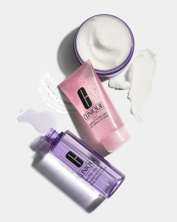 Top-down view of Clinique skincare products including a jar of cream, a pink gel tube, and a purple liquid bottle on white.