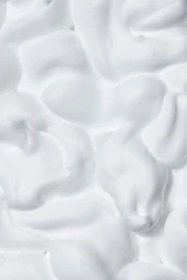 Close up view of rich white shaving foam texture with soft peaks and swirls