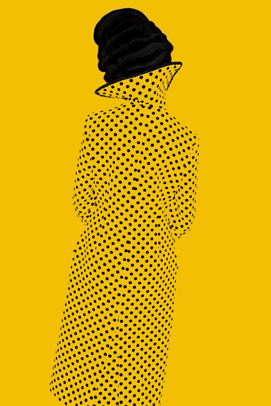 Person in a yellow coat with black polka dots and a black hat poses against a bright yellow background in a fashion shot.