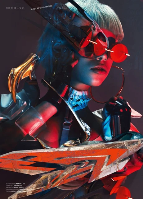 Futuristic fashion shot of person in elaborate costume with oversized sunglasses and sculptural accessories against a dark background.
