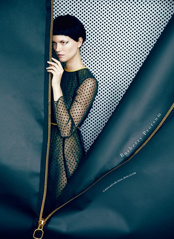 A striking fashion shot of a woman in a polka dot dress, framed by a partially unzipped blue material and a dotted backdrop.
