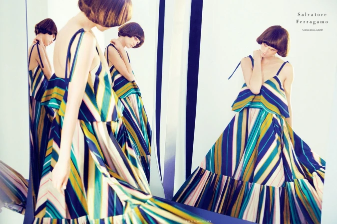 Model with bob haircut wearing a striped dress standing among multiple mirror reflections