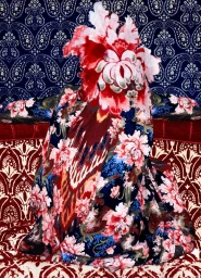 A figure completely wrapped in elaborate floral patterned textiles, seated on a patterned red and white upholstered sofa.
