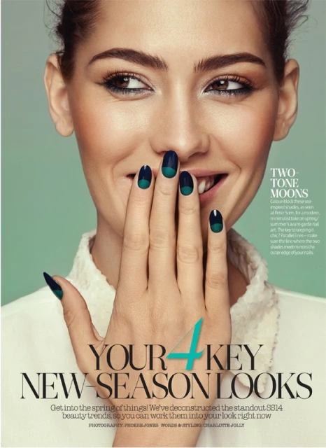Close-up beauty shot of a woman with green-and-black two-tone nail art, smiling with her hand partially covering her mouth.