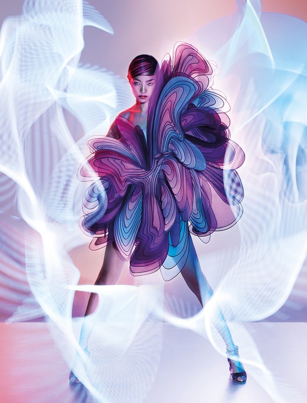 A stylish woman in an elaborate purple dress strikes a dynamic pose against a soft pink backdrop, highlighted by blue and white light effects.