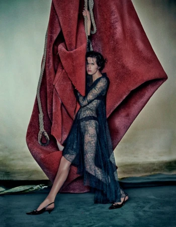 Model in sheer black lace dress posing with large red hanging textile and rope in Los Angeles styled by Anya Ziourova