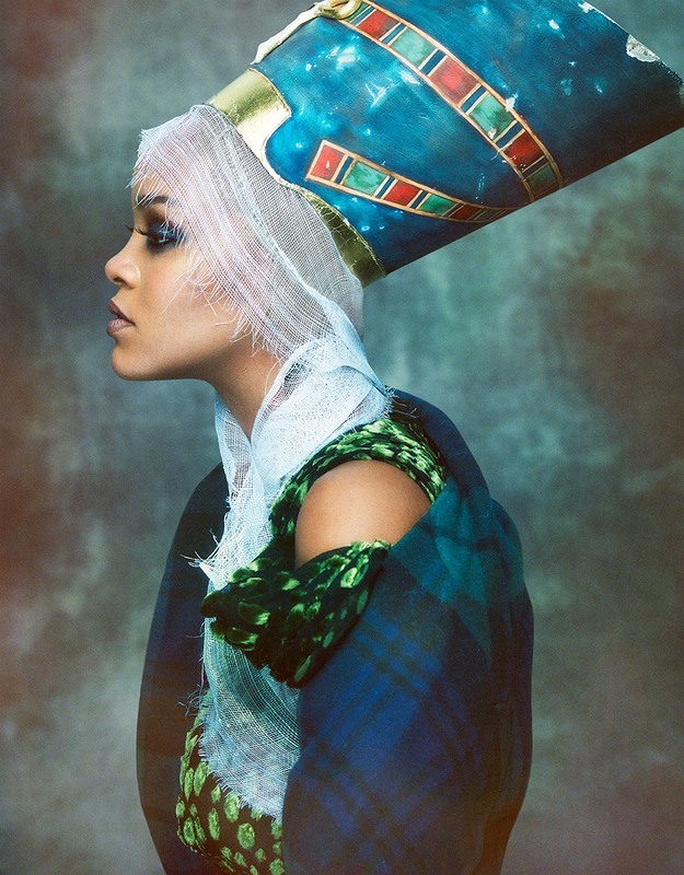Profile portrait of a woman wearing a tall blue headdress, white netting over her hair, and a dark plaid coat with green accents.
