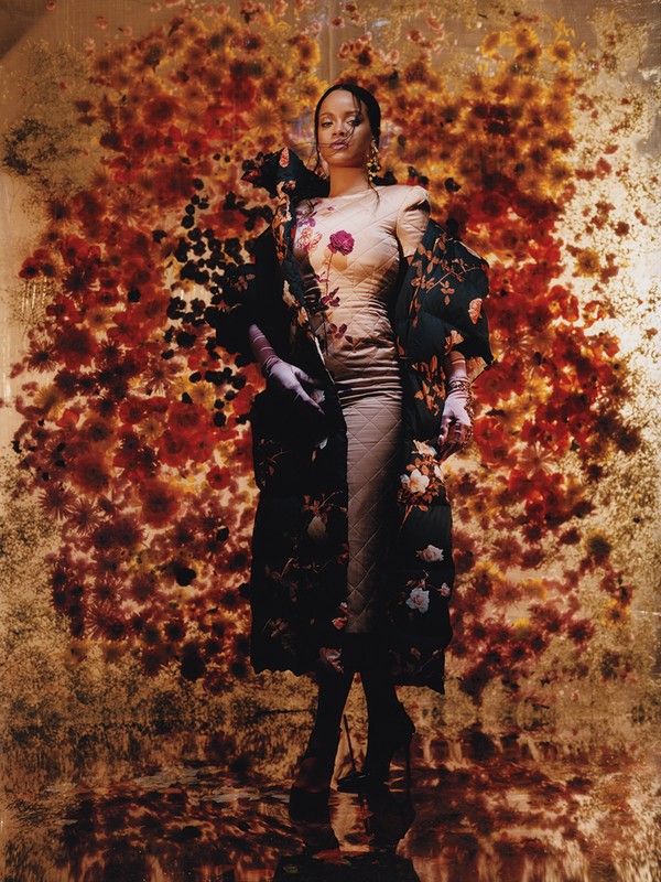 Portrait of a woman in a floral gown and matching robe, standing against a backdrop of red and orange flowers, artistic and fashionable.