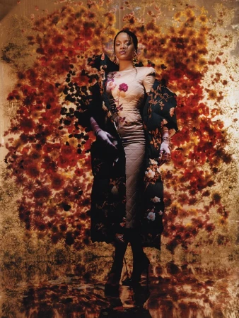 Portrait of a woman in a floral gown and matching robe, standing against a backdrop of red and orange flowers, artistic and fashionable.