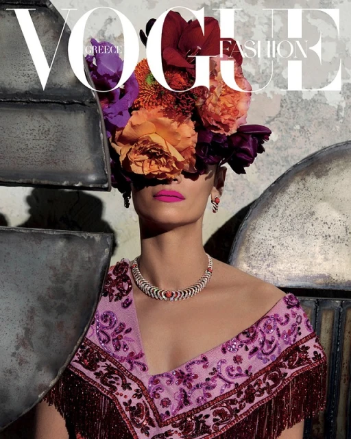 Vogue Greece cover featuring an adult female model adorned with bright flowers, statement jewelry, and magenta lipstick.