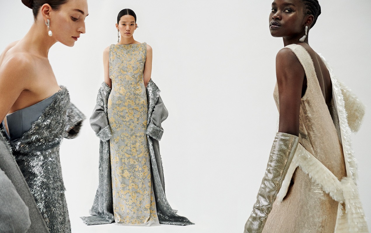 Three women in evening gowns and shimmering coats pose against a white backdrop, showcasing elegant formal wear in a studio setting.