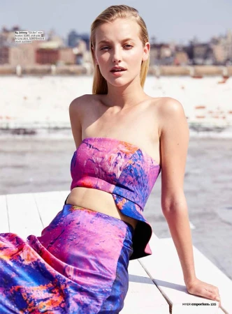 Model seated on a white wooden rooftop in Los Angeles wearing a bright pink and blue two-piece printed outfit.