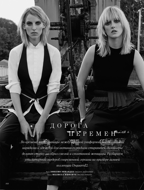 Black and white portrait featuring two fashion models in an outdoor setting with industrial elements, showcasing minimalist attire and edgy style.